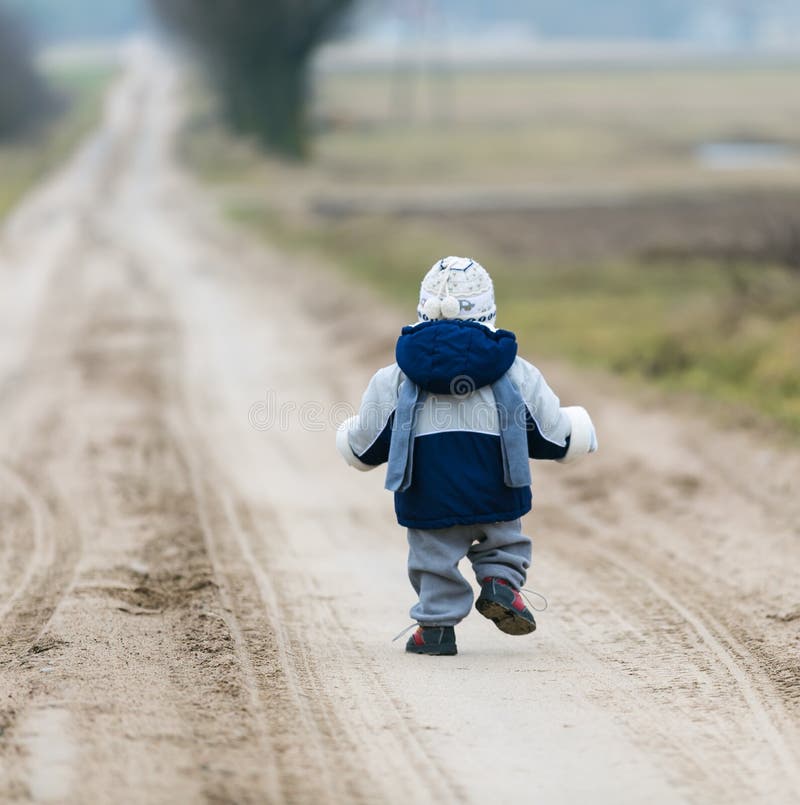 Toddler child walking by rural sandy road