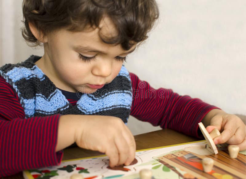Toddler doing a puzzle. Toddler doing first puzzle to learn shapes colors. Educational concept.
