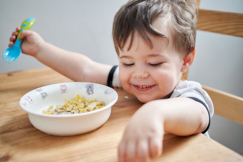 Toddler Eating Eggs for Breakfast and Fooling Around Stock Image