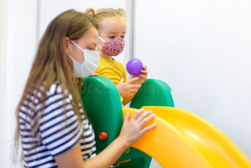 Child and therapist in sensory stimulating room, snoezelen. Autistic child  interacting with colored lights during therapy session. Stock Photo