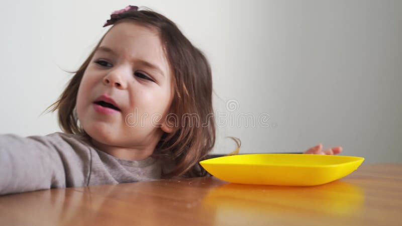 Toddler girl eating bread or pie at home with her hands. Hungry kid. Unhealthy diet. Bad table manners