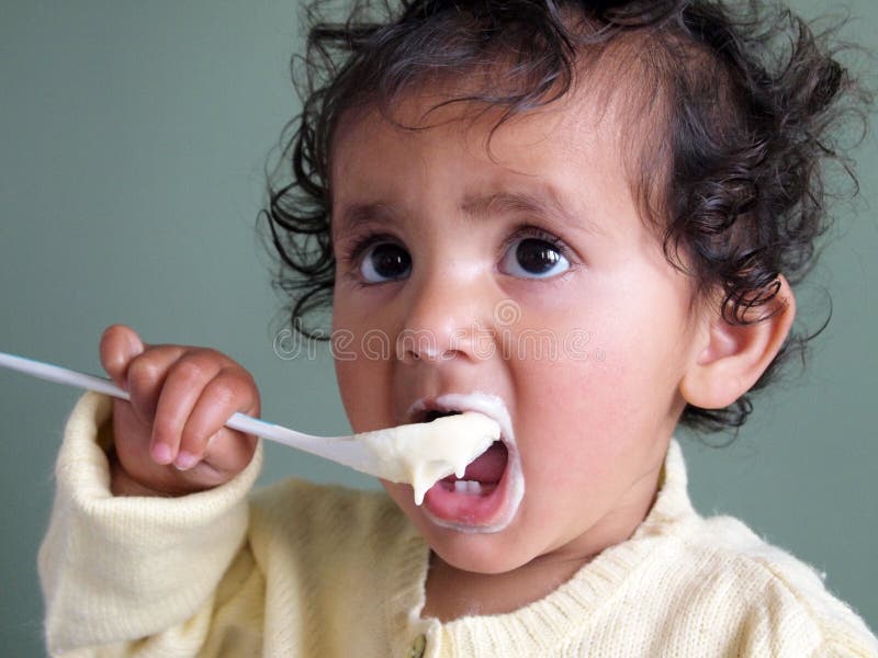 Toddler girl feeding herself with a spoon of porridge. stock images Toddler girl feeding herself with a spoon of porridge. stock images