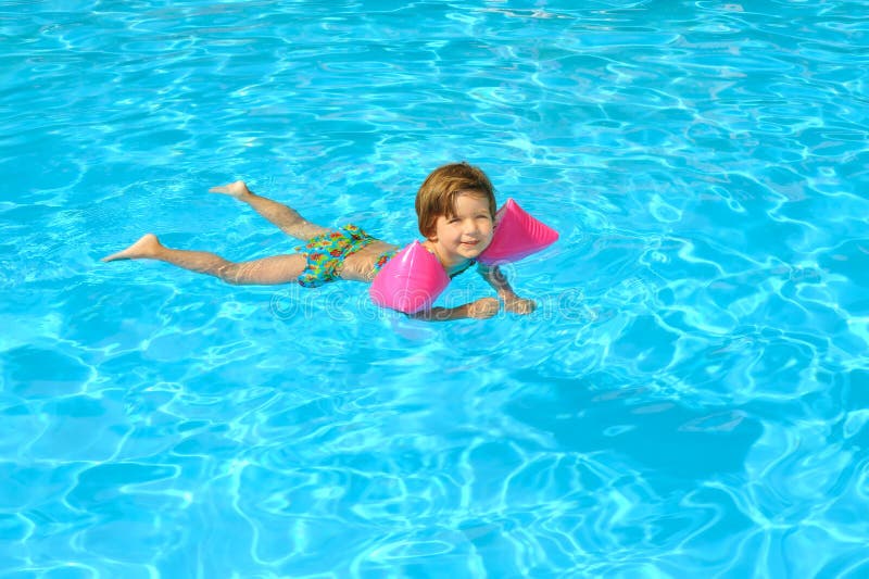 Toddler girl learning to swimm in the swimming pool