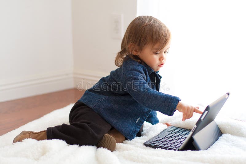 Toddler girl plays with iPad notebook stock photography Toddler girl plays with iPad notebook stock photography