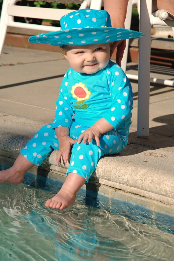 Toddler putting her feet in a swimming pool.