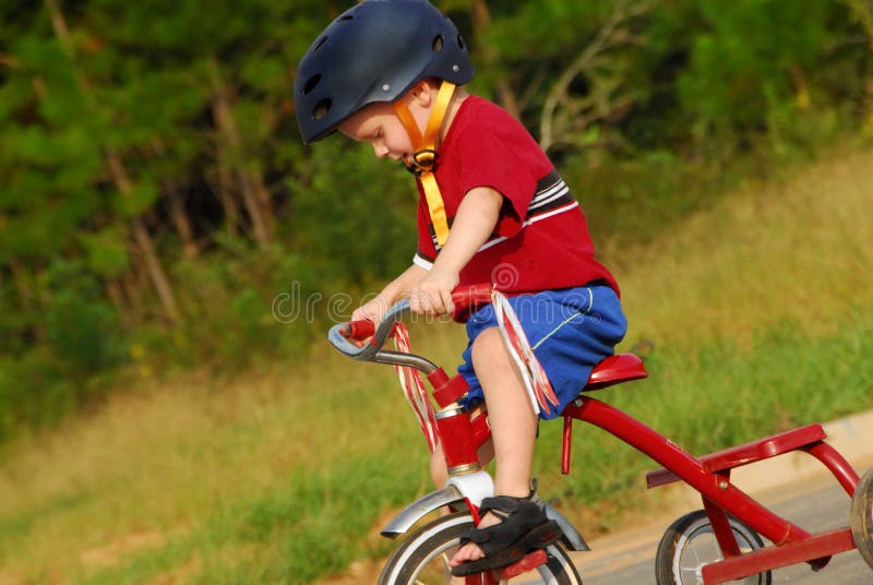 Cute young boy riding tricycle with safety helmet on head. Cute young boy riding tricycle with safety helmet on head