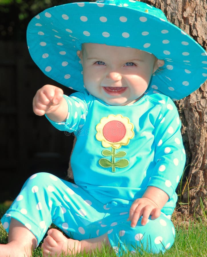 Toddler sitting on grass in a polkadot outfit