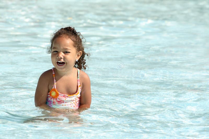 Toddler ragazza di ridere e divertirsi in una piscina.