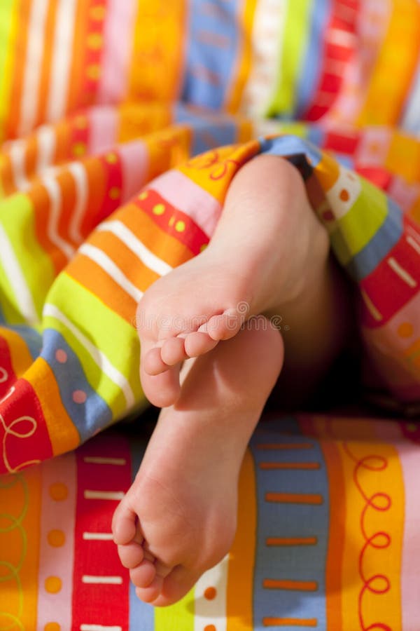 Toddlers girl feet in a bed under the morning sun stock photo Toddlers girl feet in a bed under the morning sun stock photo