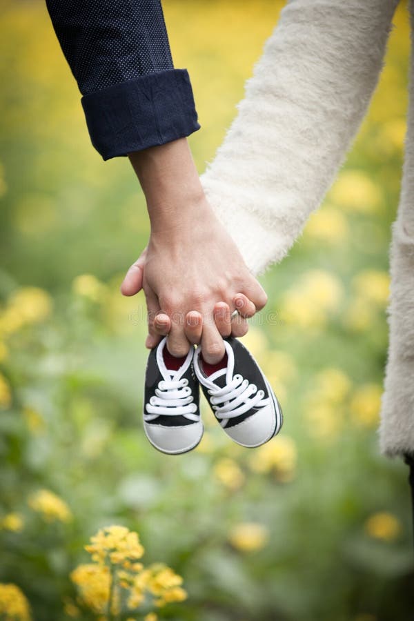 Toekomstige ouders die handen en een paar kleine schoenen houden stock fotografie Toekomstige ouders die handen en een paar kleine schoenen houden stock fotografie