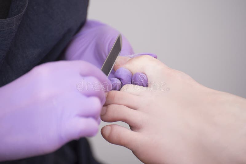 Toenails επεξεργασίας Φορημένα γάντια χέρια με ένα αρχείο καρφιών για το μανικιούρ Κινηματογράφηση σε πρώτο πλάνο στοκ εικόνα με δικαίωμα ελεύθερης χρήσης Toenails επεξεργασίας Φορημένα γάντια χέρια με ένα αρχείο καρφιών για το μανικιούρ Κινηματογράφηση σε πρώτο πλάνο στοκ εικόνα με δικαίωμα ελεύθερης χρήσης