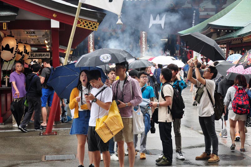 Toeristen die paraplu houden lopend of schietend terwijl het regenen voor bezoek in Sensoji-Tempel Toeristen die paraplu houden lopend of schietend terwijl het regenen voor bezoek in Sensoji-Tempel
