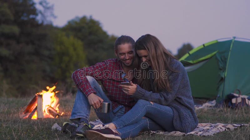 Toeristenpaar in liefde met telefoon die dichtbij in aard kamperen