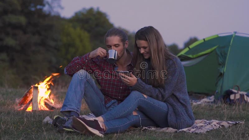 Toeristenpaar in liefde met telefoon die dichtbij in aard kamperen