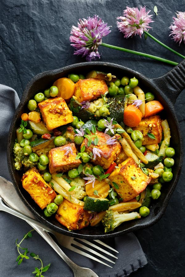 Tofu mit dem Gemüse besprüht mit Kräutern und essbaren Blumen, Draufsicht Teller des strengen Vegetariers köstlich und nahrhaft