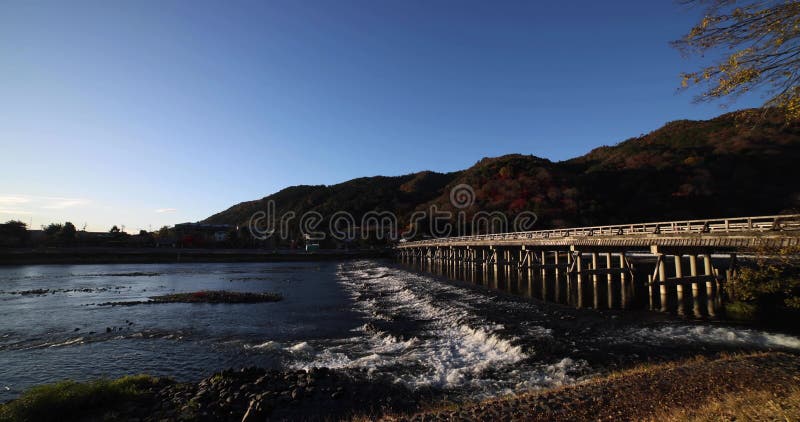 A dawn of Togetsukyo bridge near Katsuragawa river in Kyoto in autumn wide shot