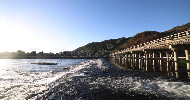 A dawn of Togetsukyo bridge near Katsuragawa river in Kyoto in autumn wide shot panning