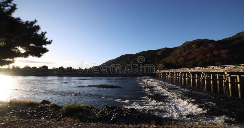 A dawn of Togetsukyo bridge near Katsuragawa river in Kyoto in autumn wide shot panning