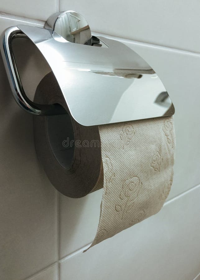 Toilet Paper Roll Hanging on Holder in Bathroom Wall Stock Photo