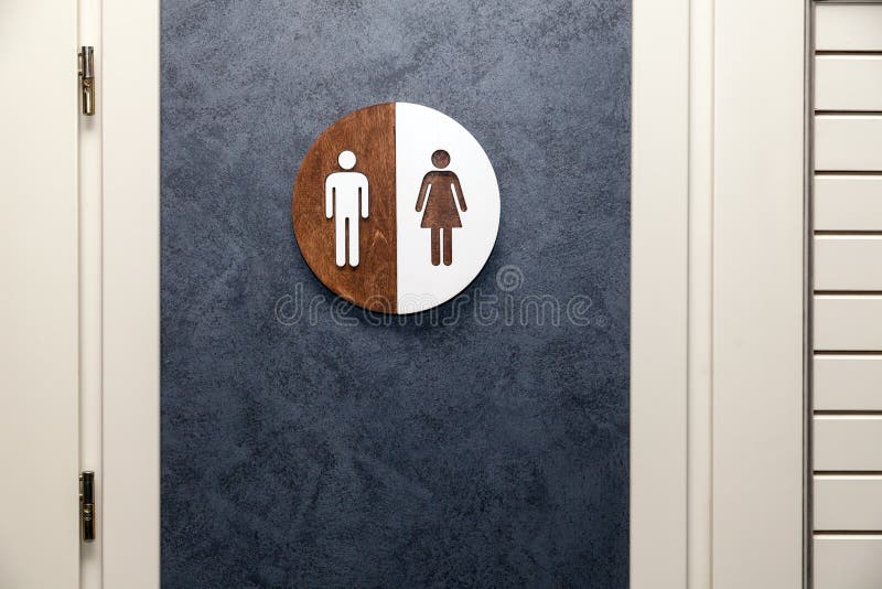 Toilet, wc icon, round wooden white and brown sign on restroom door in the hallway, restaurant, lobby. Concept sign of toilet room