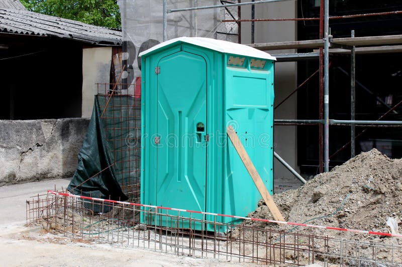 Toilette écologique portative vert clair laissée sur le chantier de construction entouré avec le sable et tout autre matériau de