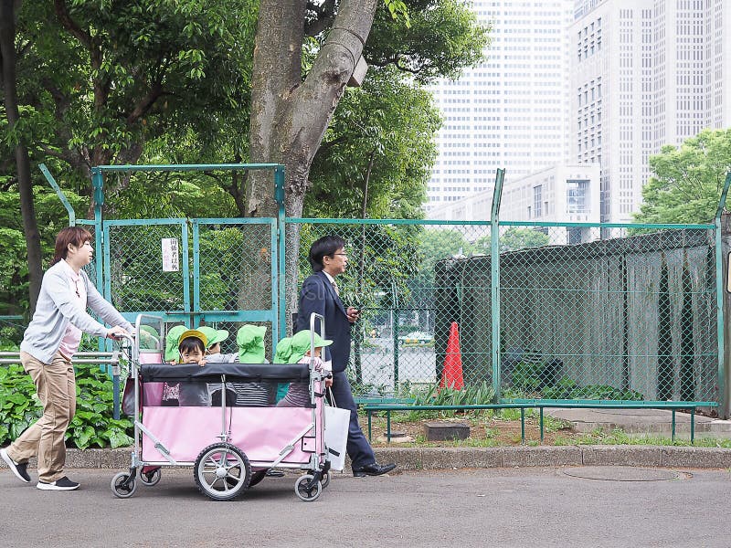 Tokyo Japan - April 22, 2018: barnkammaren tar en unge som loppet med vagnen parkerar in fotografering för bildbyråer Tokyo Japan - April 22, 2018: barnkammaren tar en unge som loppet med vagnen parkerar in fotografering för bildbyråer