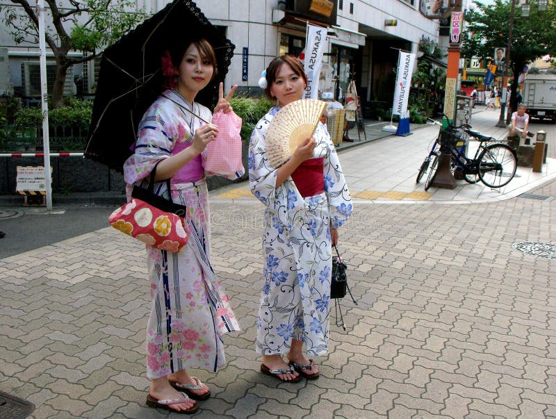 Two Japanese girls pose dressed in the traditional kimono on a Tokyo street royalty free stock photos