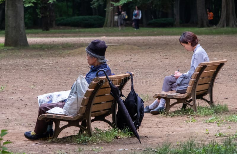 Homeless Man And Woman Sitting On Bench, Yoyogi Park Tokyo, Japan