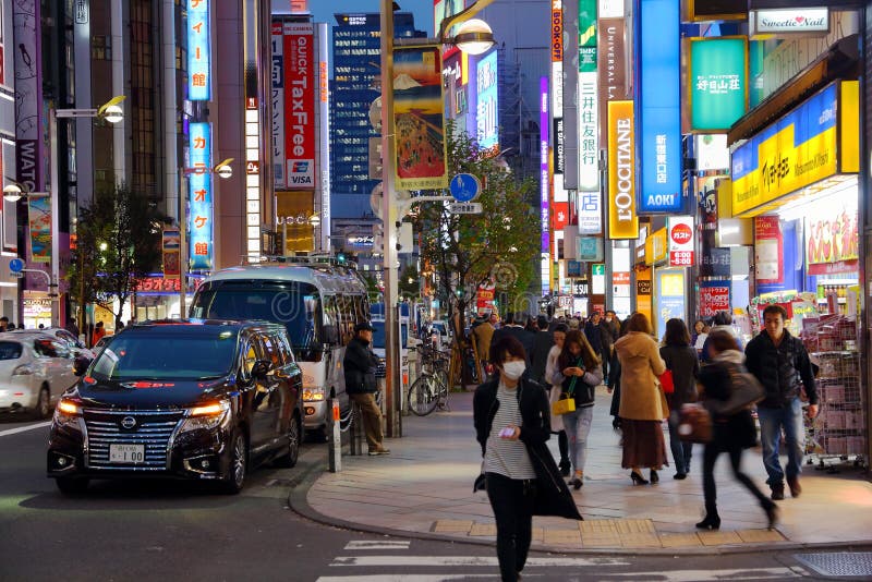 TOKYO, JAPON - 30 NOVEMBRE 2016 : Les gens marchent sous les lampes au néon du secteur de Shinjuku de Tokyo, Japon r images libres de droits TOKYO, JAPON - 30 NOVEMBRE 2016 : Les gens marchent sous les lampes au néon du secteur de Shinjuku de Tokyo, Japon r images libres de droits