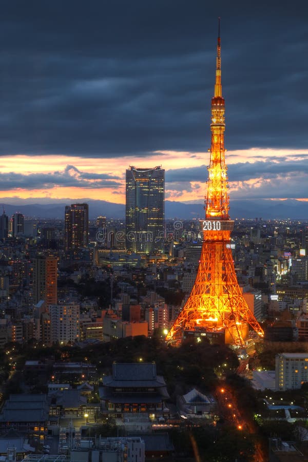 Twilight view of Tokyo Tower from a high perspective point (World Trade Center Building in Hamamatsucho, Tokyo, Japan). The Mori Tower of the Roppongi Hills complex, another landmark building of the city is also visible in the background. At the foot of the tower lies the Zozo-ji Temple, another religious highlight. Dramatic sunset cloudscape provides the perfect backdrop for the scene. Twilight view of Tokyo Tower from a high perspective point (World Trade Center Building in Hamamatsucho, Tokyo, Japan). The Mori Tower of the Roppongi Hills complex, another landmark building of the city is also visible in the background. At the foot of the tower lies the Zozo-ji Temple, another religious highlight. Dramatic sunset cloudscape provides the perfect backdrop for the scene.