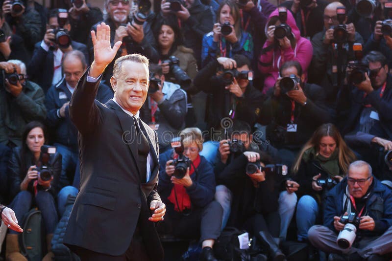 Rome, Italy - October 13, 2016: Tom Hanks on the red carpet at the Rome Film Fest 2016 American actor Tom Hanks on the red carpet at the 11th Film Festival in Rome, Hank greets the audience, raising his arm, and behind him a crowd of photographers take it back. Rome, Italy - October 13, 2016: Tom Hanks on the red carpet at the Rome Film Fest 2016 American actor Tom Hanks on the red carpet at the 11th Film Festival in Rome, Hank greets the audience, raising his arm, and behind him a crowd of photographers take it back.