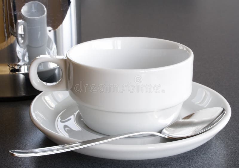 Reflective coffee pot next to an empty white cup. Reflective coffee pot next to an empty white cup.