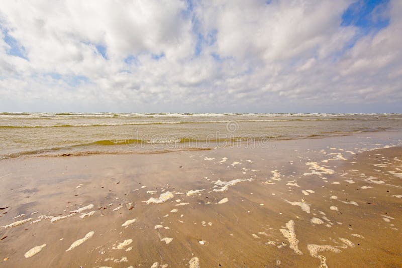 Tom strand för baltiskt hav på en solig dag med mjuka moln. Blöta stranden med mjuka moln i himlen i Liepaja, Lettland