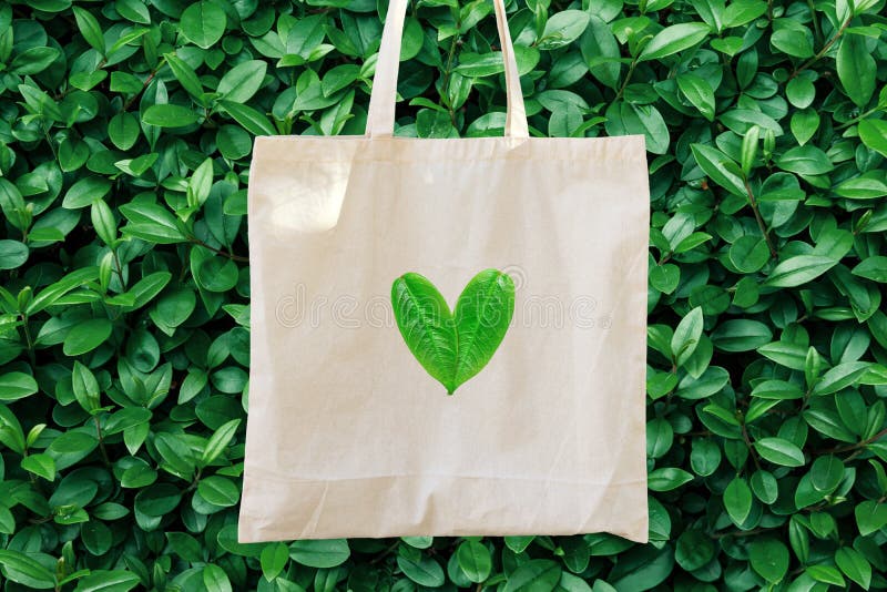 Tom vit modelllinnebomull Tote Bag på grön bakgrund för Bush trädlövverk Hjärtalogo från sidor Vänlig stil för natur royaltyfri bild