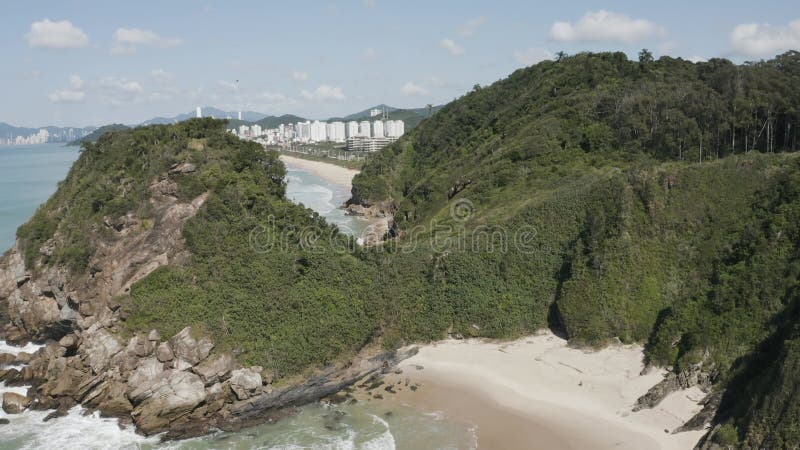 Toma de drones de una ciudad costera que bordea una hermosa playa de arena. almacen de metraje de vídeo