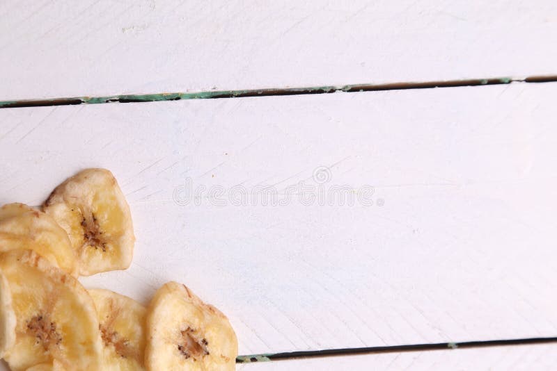 Toma de gran angular de un montón de plátanos secos aislados en una superficie de madera blanca imagen de archivo