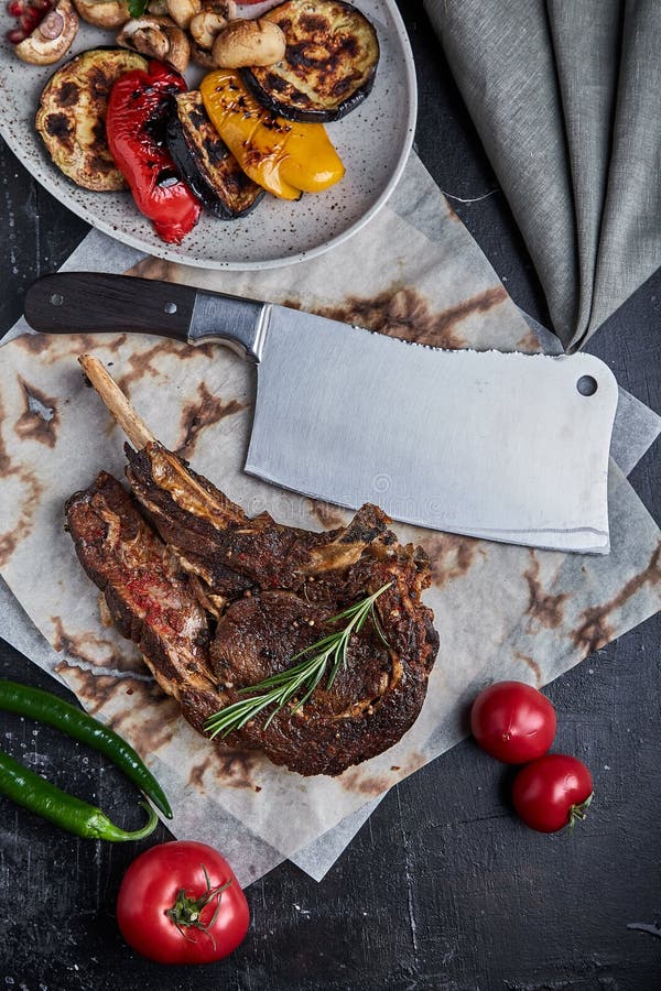Tomahawk Steak with Vegetables and a Knife on the Table. Grilled Meat with Grilled Vegetables