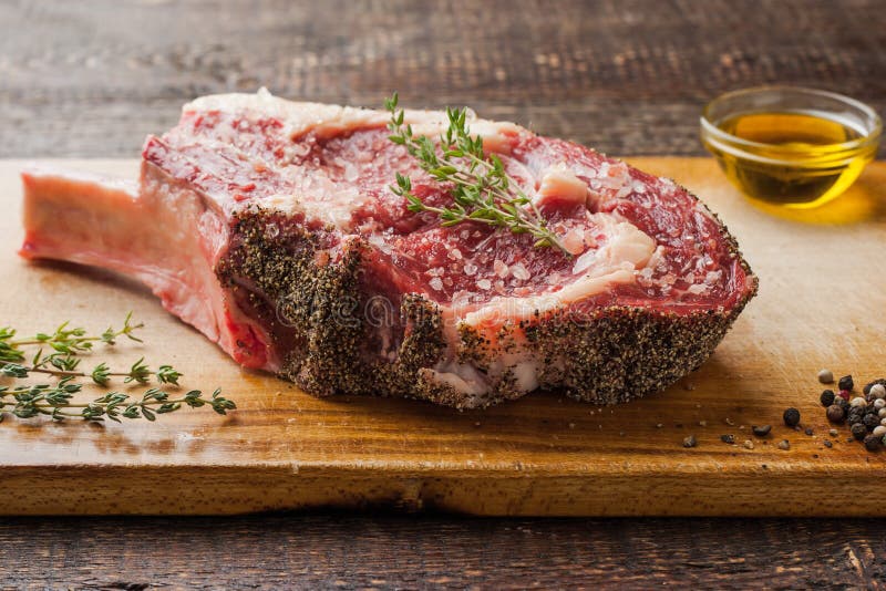 Tomahawklapje vlees op het been met thyme op scherpe raad stock afbeelding Tomahawklapje vlees op het been met thyme op scherpe raad stock afbeelding