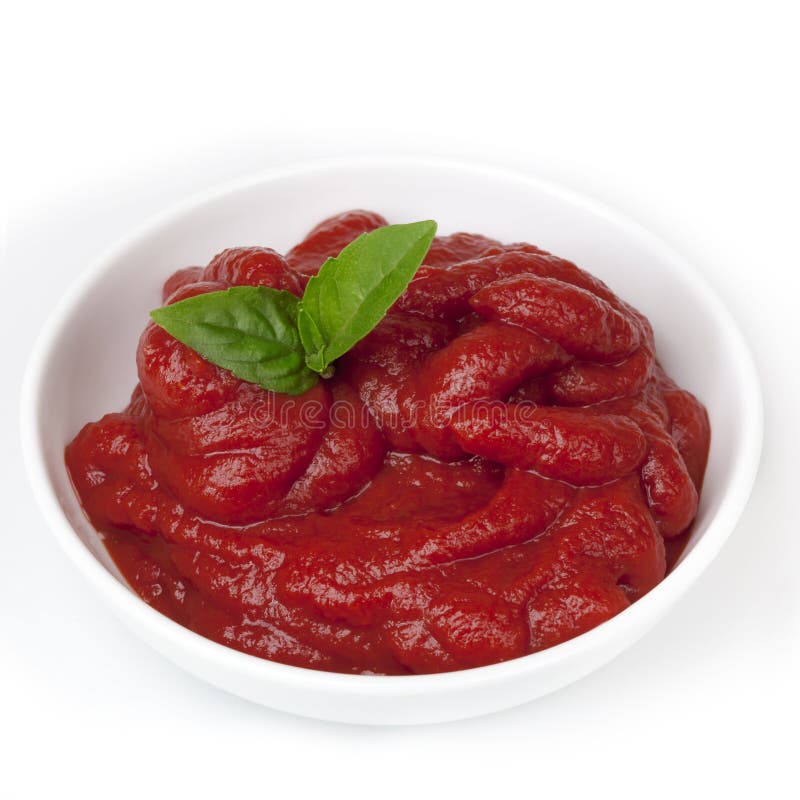 Tomato paste in small white bowl, with basil. Tomato paste in small white bowl, with basil.