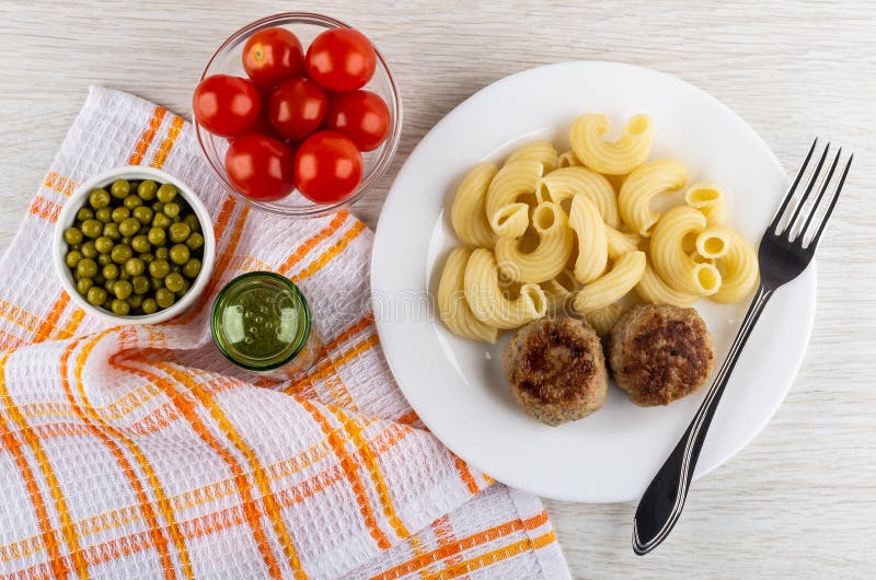 Tomate dans la cuvette, pois dans la cuvette, poivre sur la serviette, plat avec les pâtes cuites, petits pâtés frits, fourchette image stock Tomate dans la cuvette, pois dans la cuvette, poivre sur la serviette, plat avec les pâtes cuites, petits pâtés frits, fourchette image stock