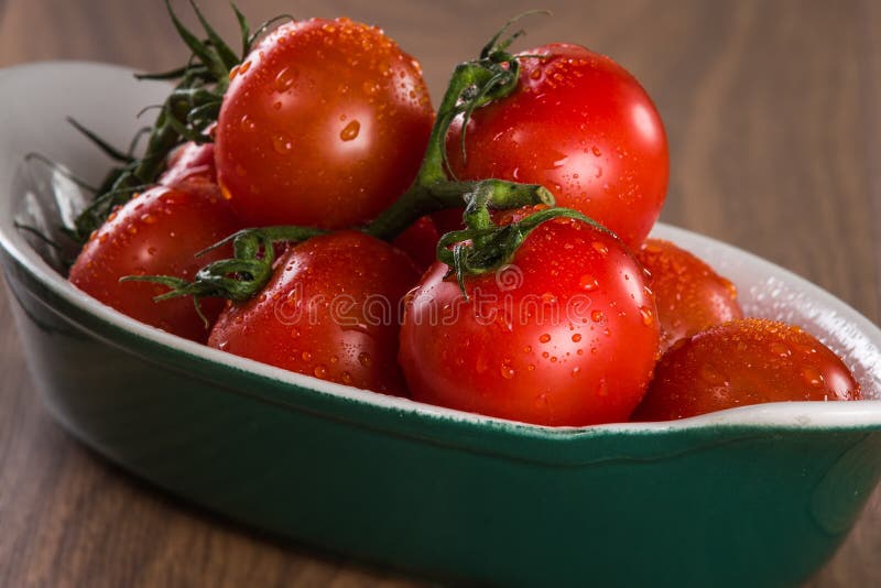 Tomates-cerises mûres dans une cuvette sur une table en bois image libre de droits Tomates-cerises mûres dans une cuvette sur une table en bois image libre de droits