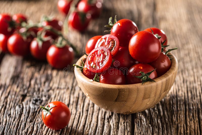 Tomates de cereja frescos na bacia de madeira na tabela de carvalho velha imagem de stock royalty free Tomates de cereja frescos na bacia de madeira na tabela de carvalho velha imagem de stock royalty free