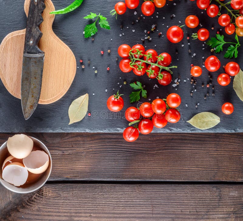 Tomates de cereza rojos maduros, tabla de cortar con un cuchillo viejo y una cáscara de los huevos del pollo fotografía de archivo Tomates de cereza rojos maduros, tabla de cortar con un cuchillo viejo y una cáscara de los huevos del pollo fotografía de archivo