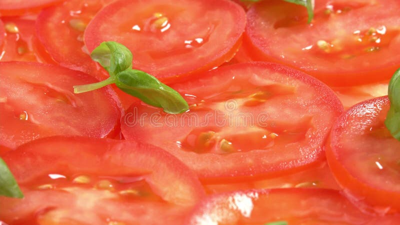 Tomates recién cortados con hojas de albahaca frescas como el carpaccio de tomate rotan como fondo. preparaciones para pizza o almacen de video
