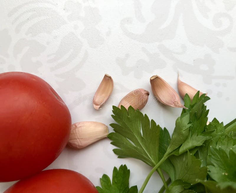 Tomates rouges, persil vert juteux, clous de girofle d'ail sur le fond clair photo libre de droits Tomates rouges, persil vert juteux, clous de girofle d'ail sur le fond clair photo libre de droits