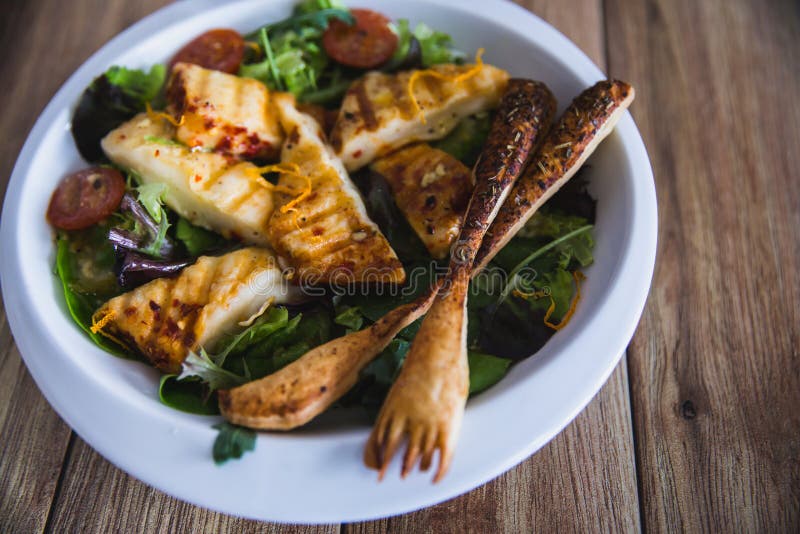 Tomates y lechuga asados a la parrilla de la bruja de la ensalada del queso de Halloumi en la placa blanca en fondo de madera Ali fotos de archivo libres de regalías Tomates y lechuga asados a la parrilla de la bruja de la ensalada del queso de Halloumi en la placa blanca en fondo de madera Ali fotos de archivo libres de regalías