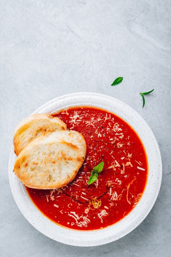 Tomato Basil Soup with Parmesan Cheese and Bread Toasts on Gray Stone