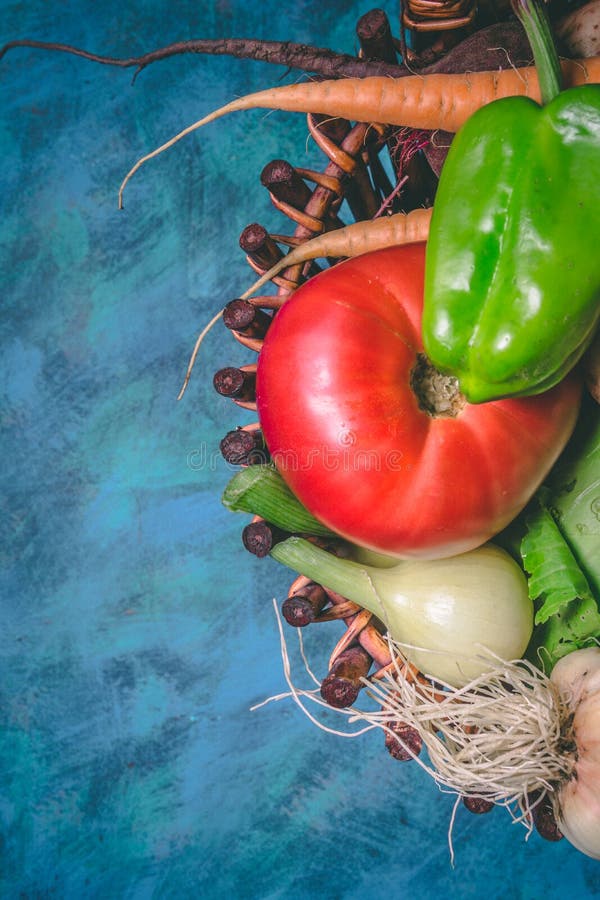 Tomato, cabbage, onion, potato, pepper, garlic, carrot and beetroot. Vegetables in a basket on a blue background. Copy space.