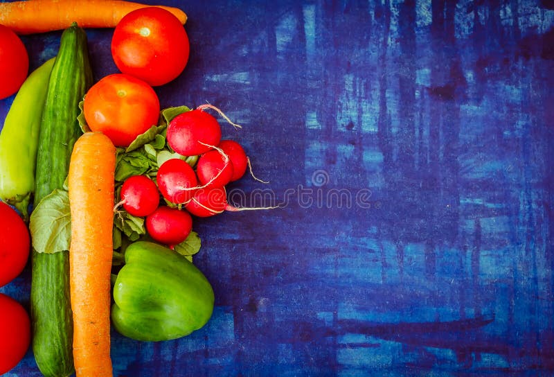 Tomato with capsicum, radish, carrot, and cucumber on blue background. Healthy vegetable food concept.