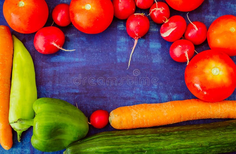 Tomato with cucumber, radish, capsicum and carrot on blue background. Healthy vegetable food concept.